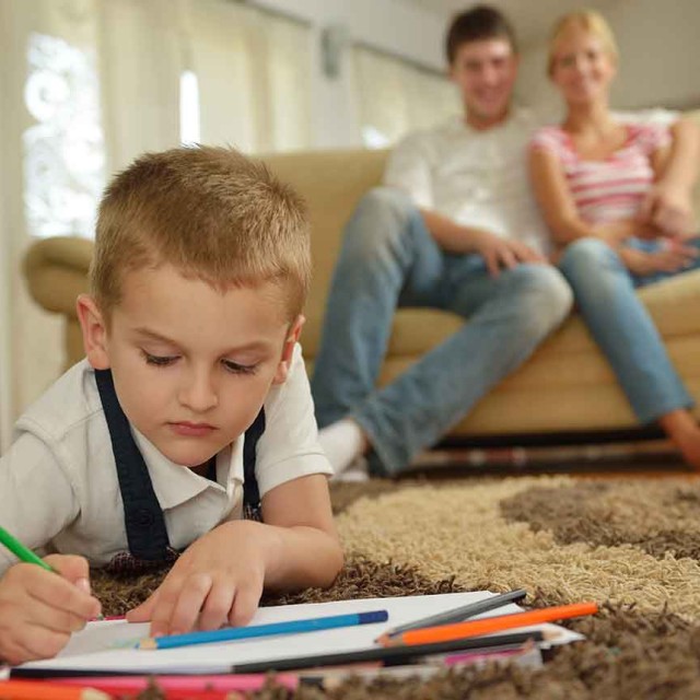 child-drawing-on-floor-with-parents-looking-on
